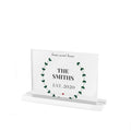 Clear acrylic sign with a green leaf wreath around home sweet home, The Smiths and Est. 2020